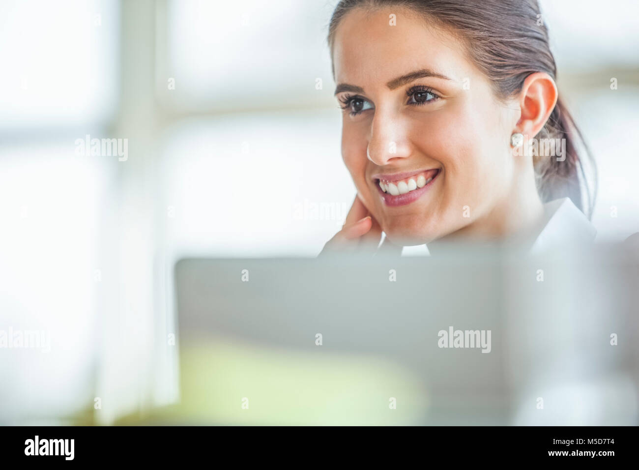 Smiling young businesswoman looking away in office Stock Photo - Alamy