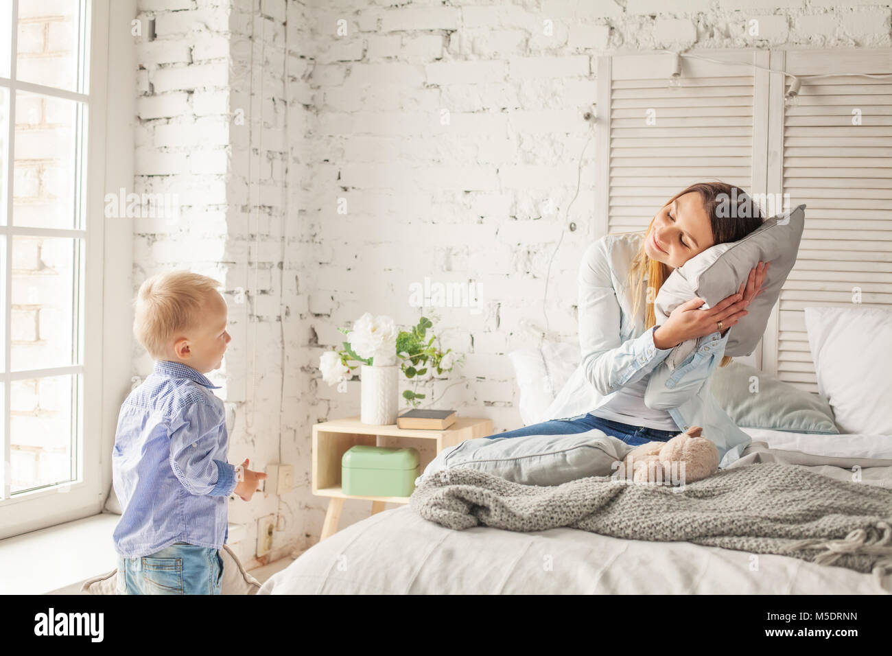 Tired Mother and Small Son in Bedroom at Home Stock Photo