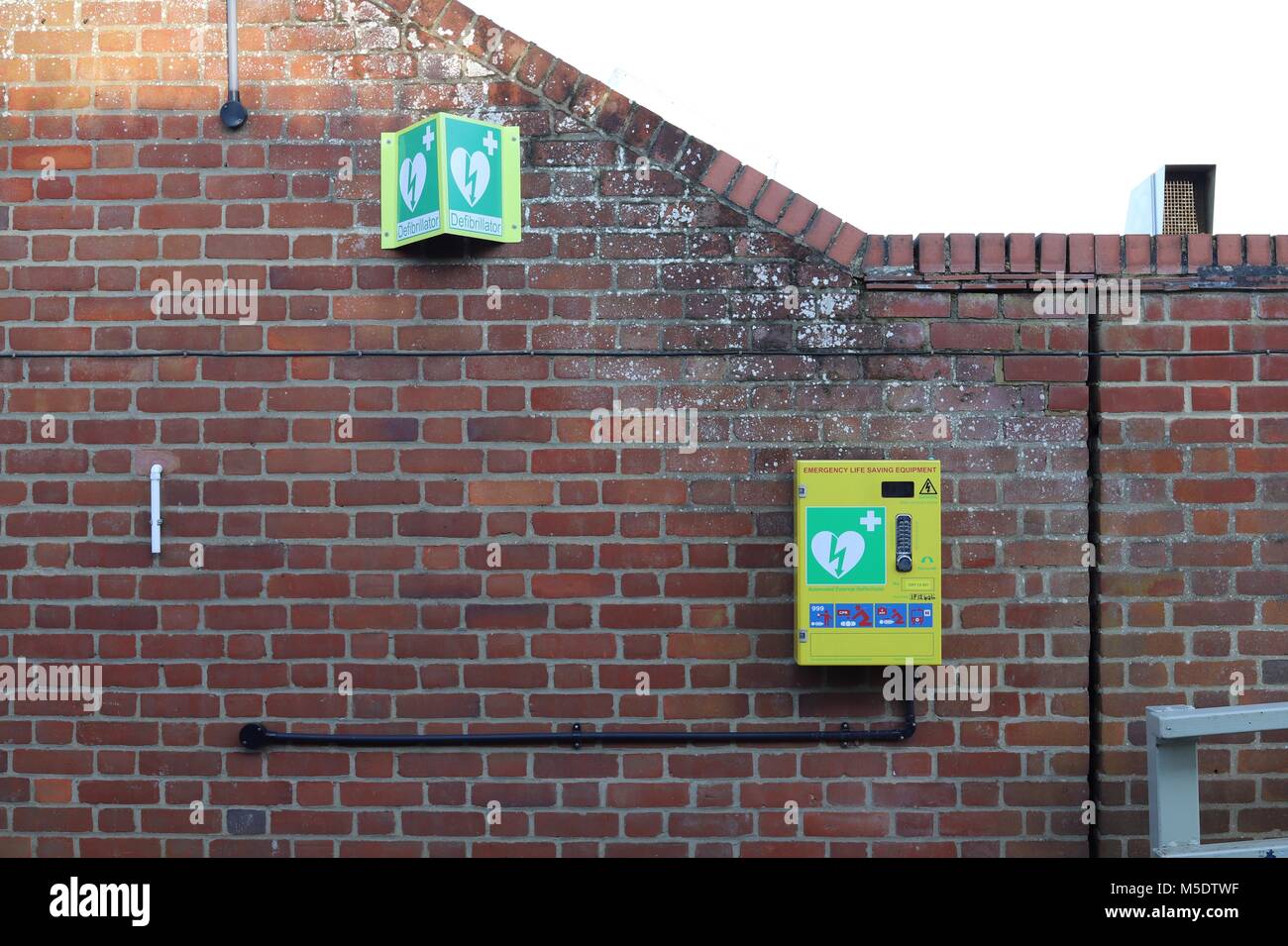 Defibrillator / emergency life saving equipment with code lock wall mounted for public use. Outside The Maybush pub in Waldringfield, Suffolk. Stock Photo