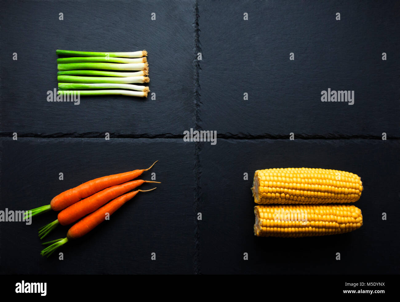 Three organic root vegetables on slate tablets, onions, carrots and ...