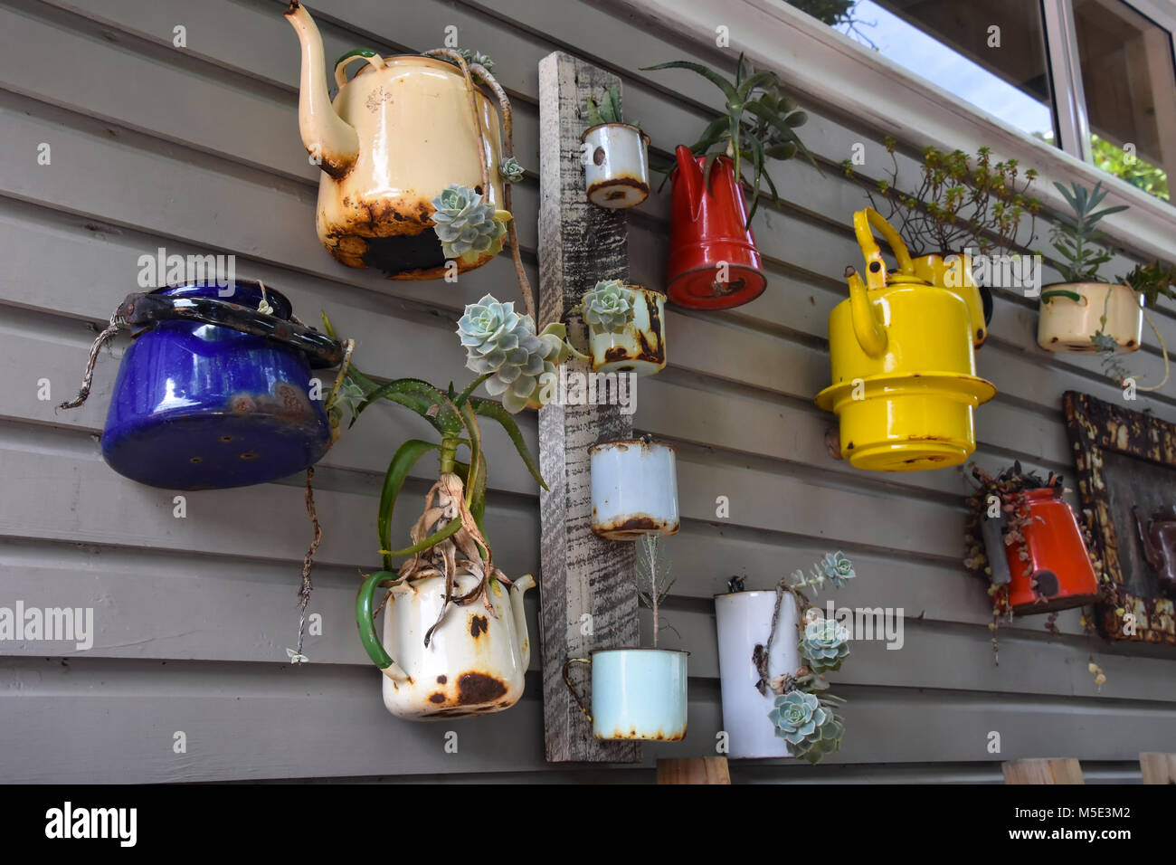 A collection of teapots and kettles on display hanging on the wall as decoration taken on the