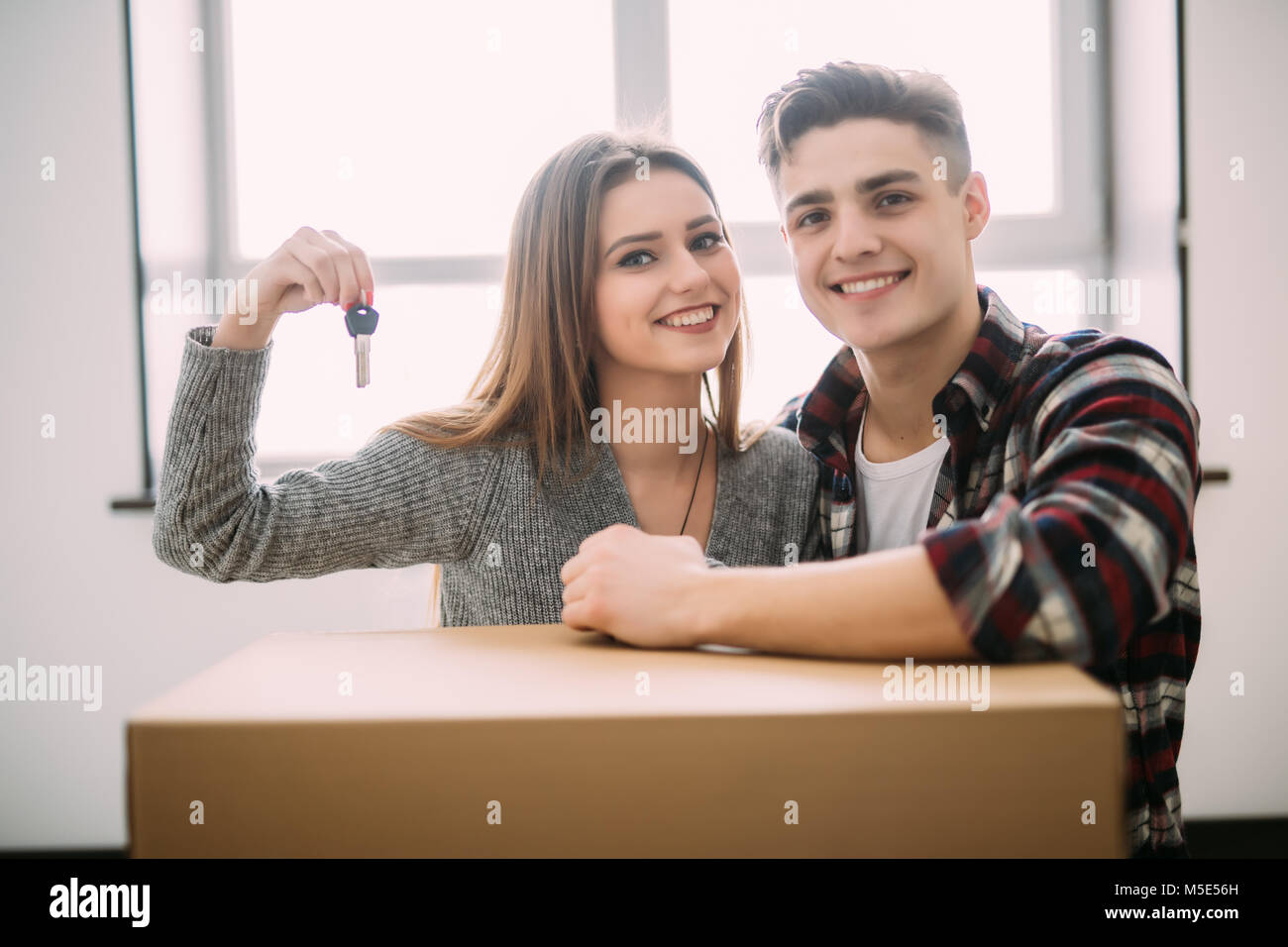 happy young couple holding the keys of their new home with moving ...