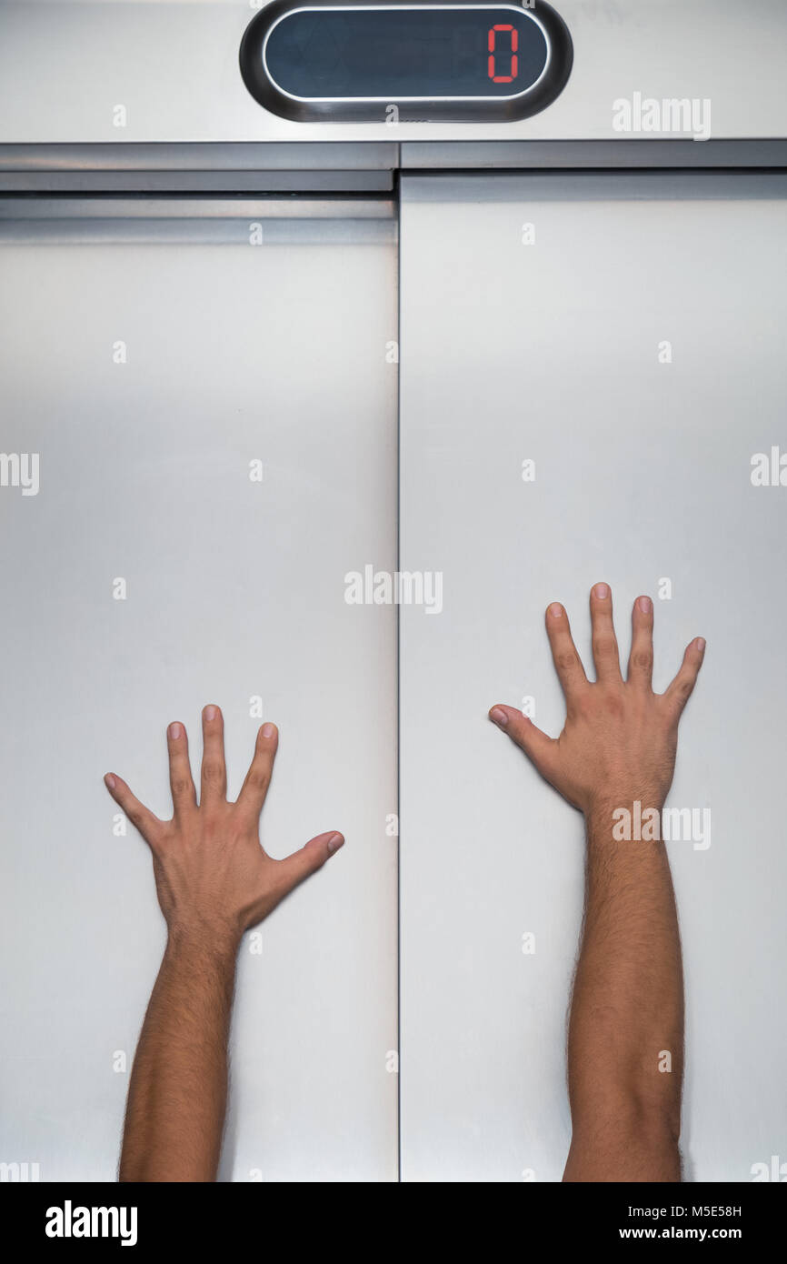 Man hands try to stop and prevent closing elevator door Stock Photo