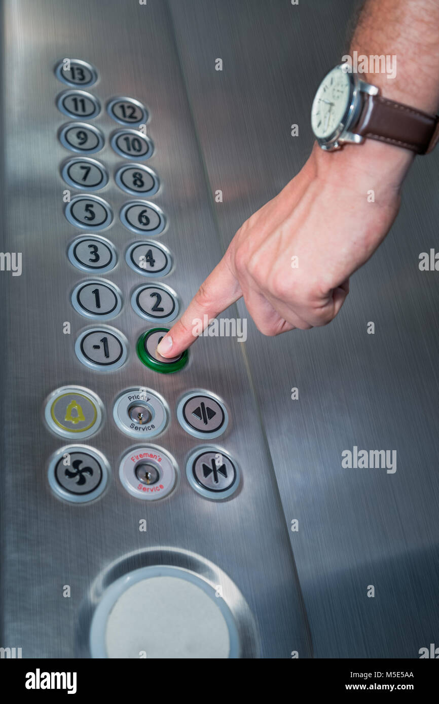 Close up of male forefinger pressing the zero floor button in the elevator. Iron made interior. Stock Photo