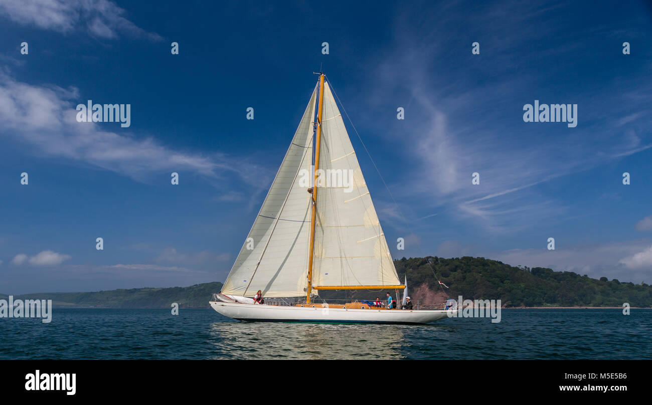 The classic wooden yacht Sibyl Of Cumae under sail off the Cornish coast on a calm sunny day. Stock Photo