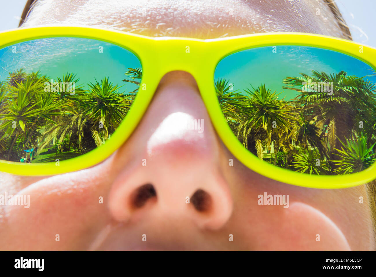 Close up of female wearing sunglasses and palm trees reflection. Summer vacation and exotic destinations concepts. Stock Photo