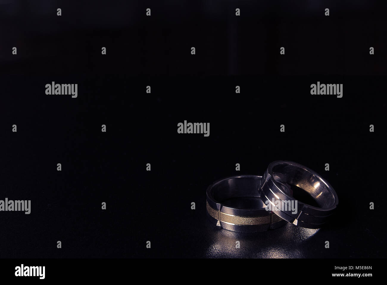 Two golden wedding rings on black background. Space for copy. Love and