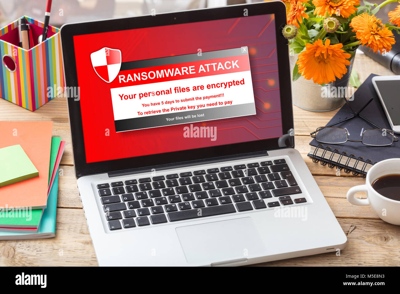 Ransomware attack message on a computer screen on a wooden office desk Stock Photo