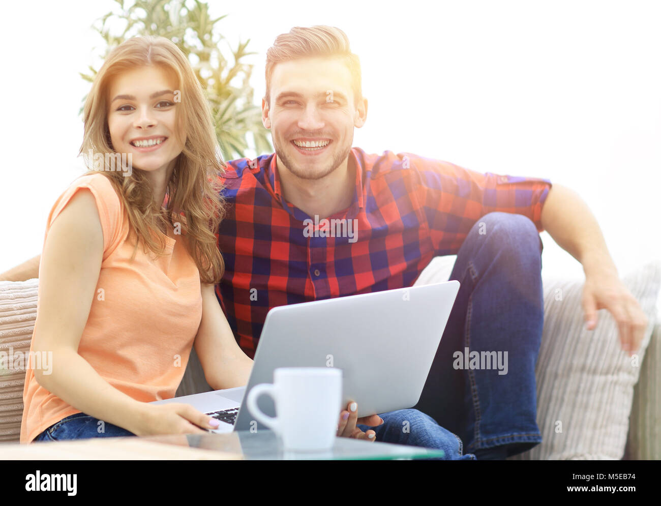 young couple of students uses a laptop sitting on sofa Stock Photo - Alamy