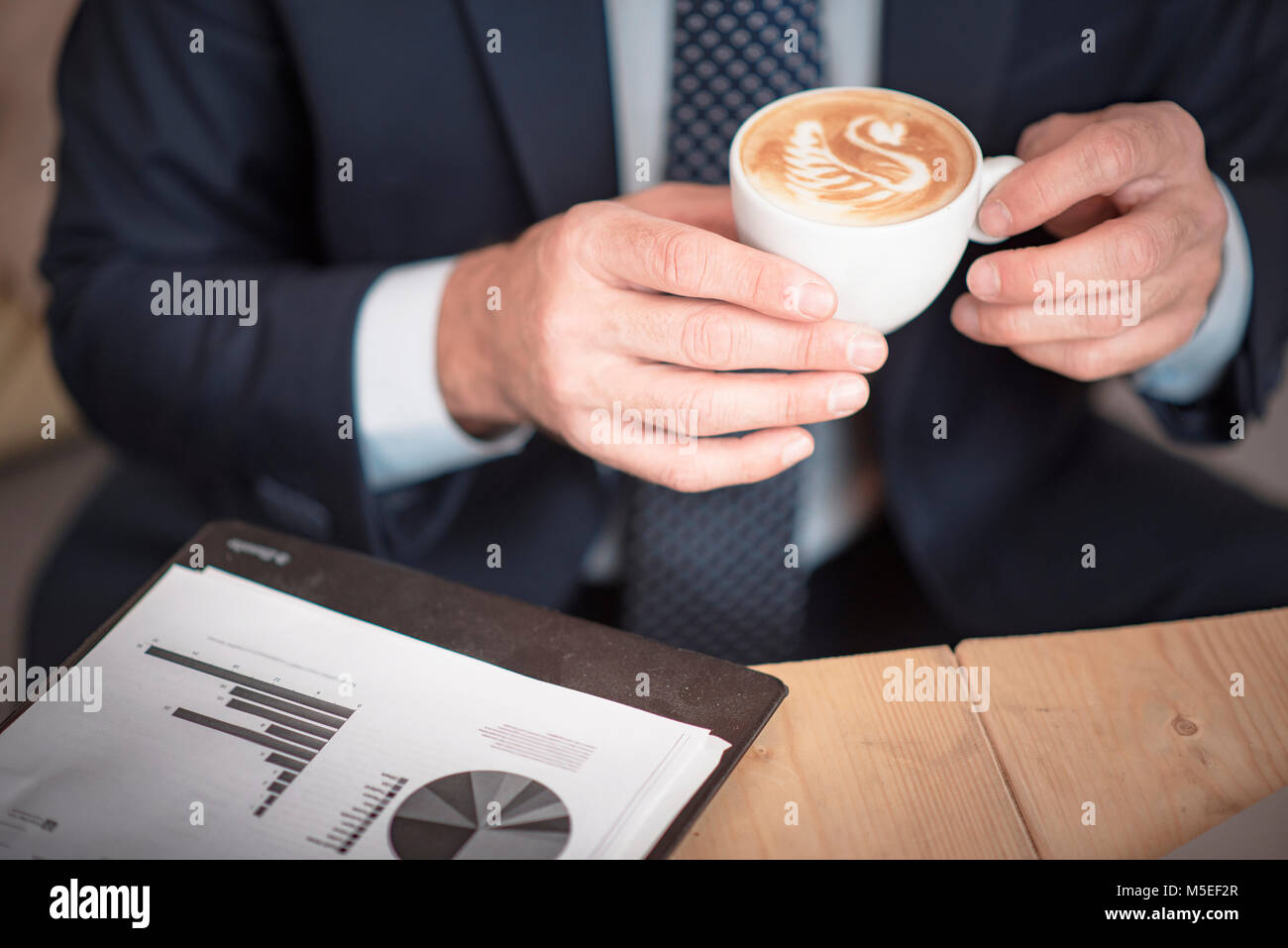 Senior mature business man having a coffee in a coffee shop, reviewing charts and graphs Stock Photo