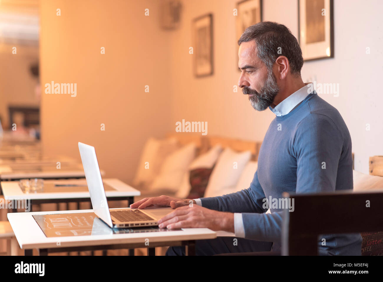 Senior retired man sitting in a coffee shop and using his laptop Stock Photo