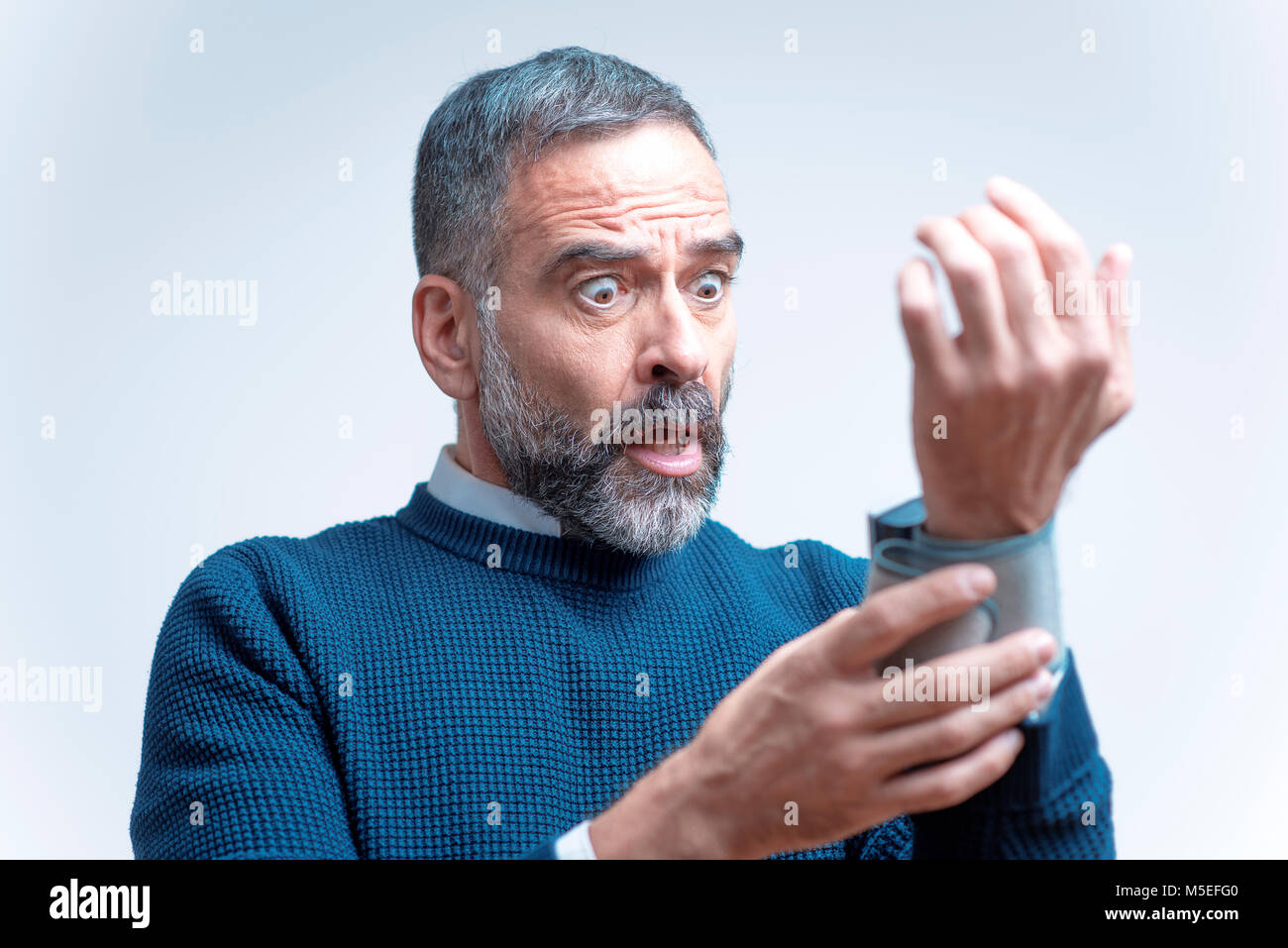 Senior man shocked and outraged with his blood pressure measurement result, studio image Stock Photo