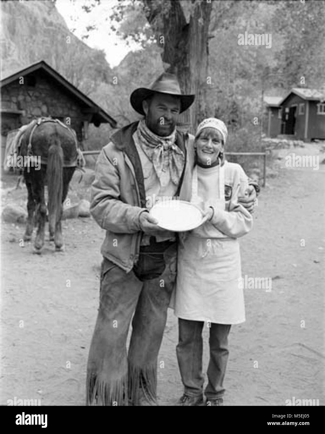 Grand Canyon Historic - Phantom Ranch Employees   PHANTOM RANCH STAFF, ROSS KNOX, XANTERRA PACKER, AND ELAINE MUIR-TRACEY,  SPOUSE OF PHANTOM RANCH MANAGER,  WARREN TRACEY HOLDING A CREAM PIE MADE IN THE PHANTOM RANCH KITCHEN. THE PHOTO WAS  TAKEN AS A JOKE, TO SUGGEST IT WOULD BE THROWN AT LIVERY MANAGER, RON CLAYTON - AS A REPARATION. Stock Photo