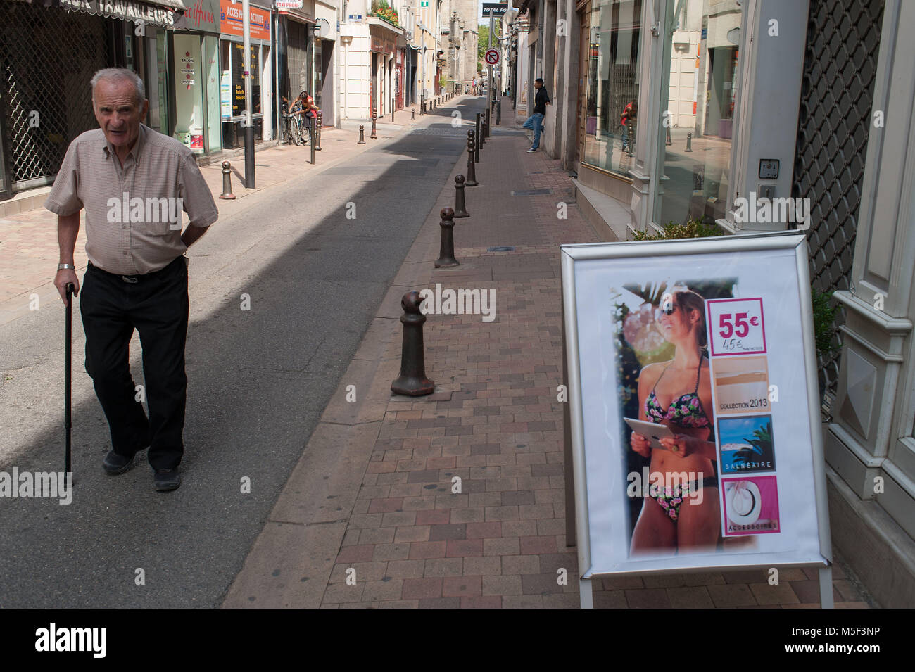 Carcassonne, France. Old man with stick and advertising of female swimsuits for women. Stock Photo