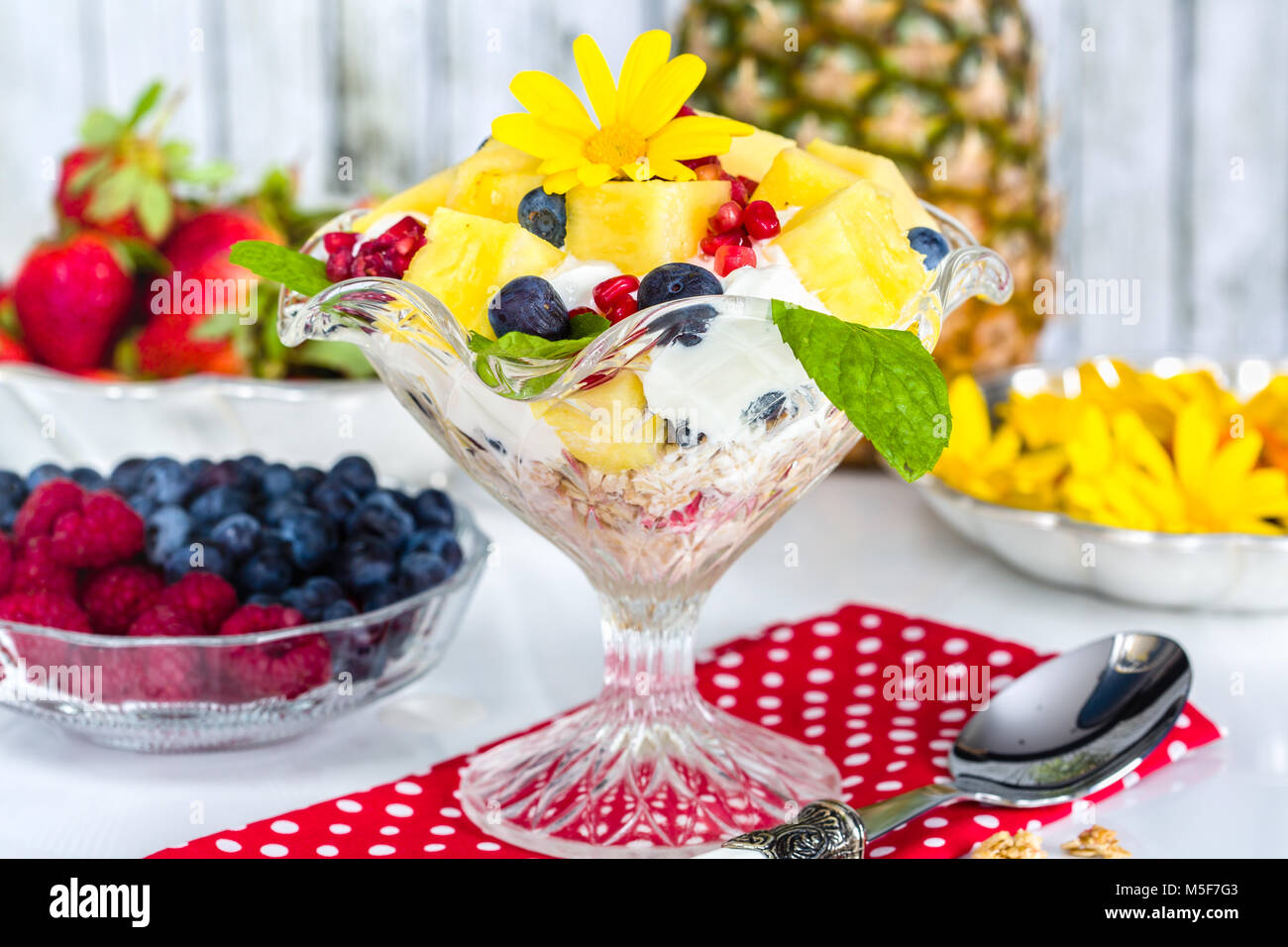 Fresh breakfast with muesli, yoghurt, fruit and edible flowers Stock Photo