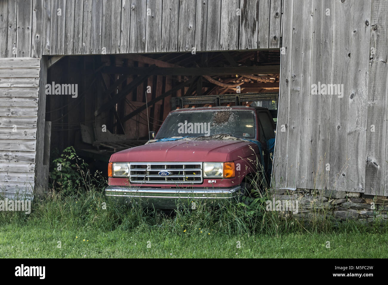 Old abandoned vehicle in a wooden barn. Stock Photo