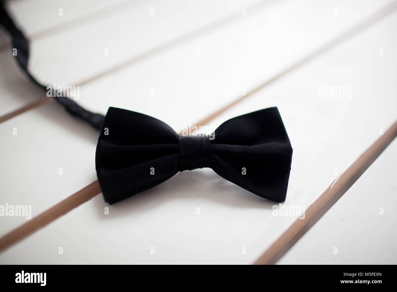 Black bow tie isolated on white background. Wooden white background Stock Photo