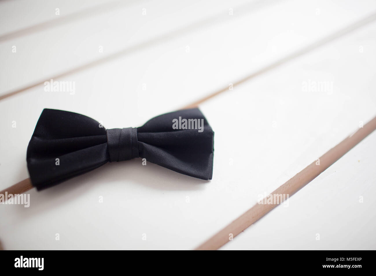 Black bow tie isolated on white background. Wooden white background Stock Photo