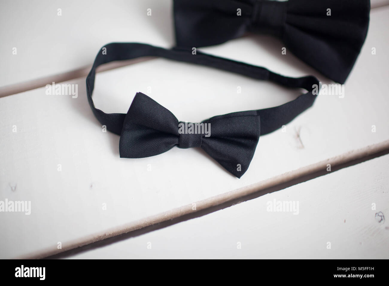 Black bow tie isolated on white background. Wooden white background Stock Photo