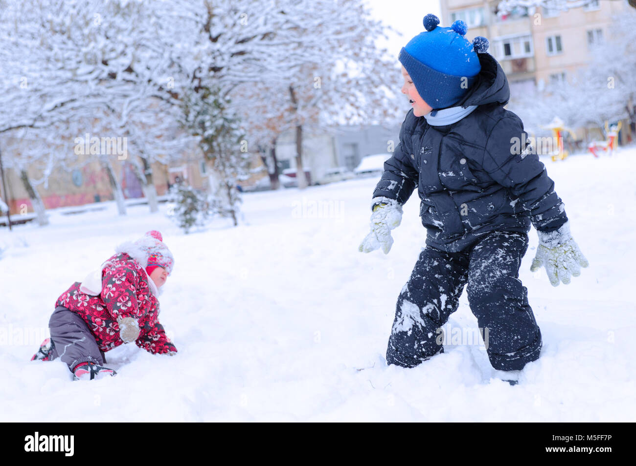Two happy children playing snowball on snowy field Stock Photo - Alamy