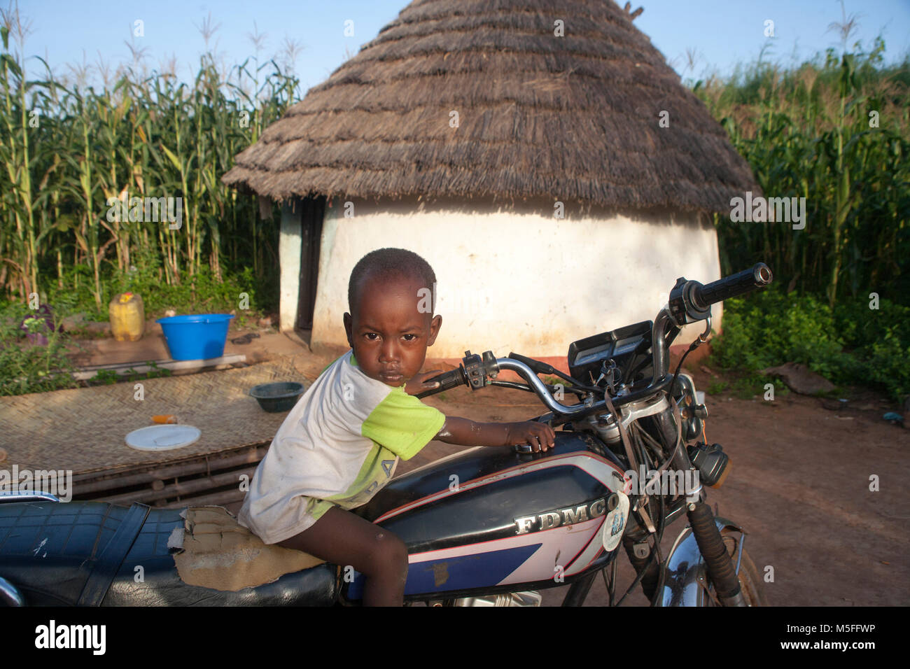 Small African boy sits on his father's bicycle Stock Photo