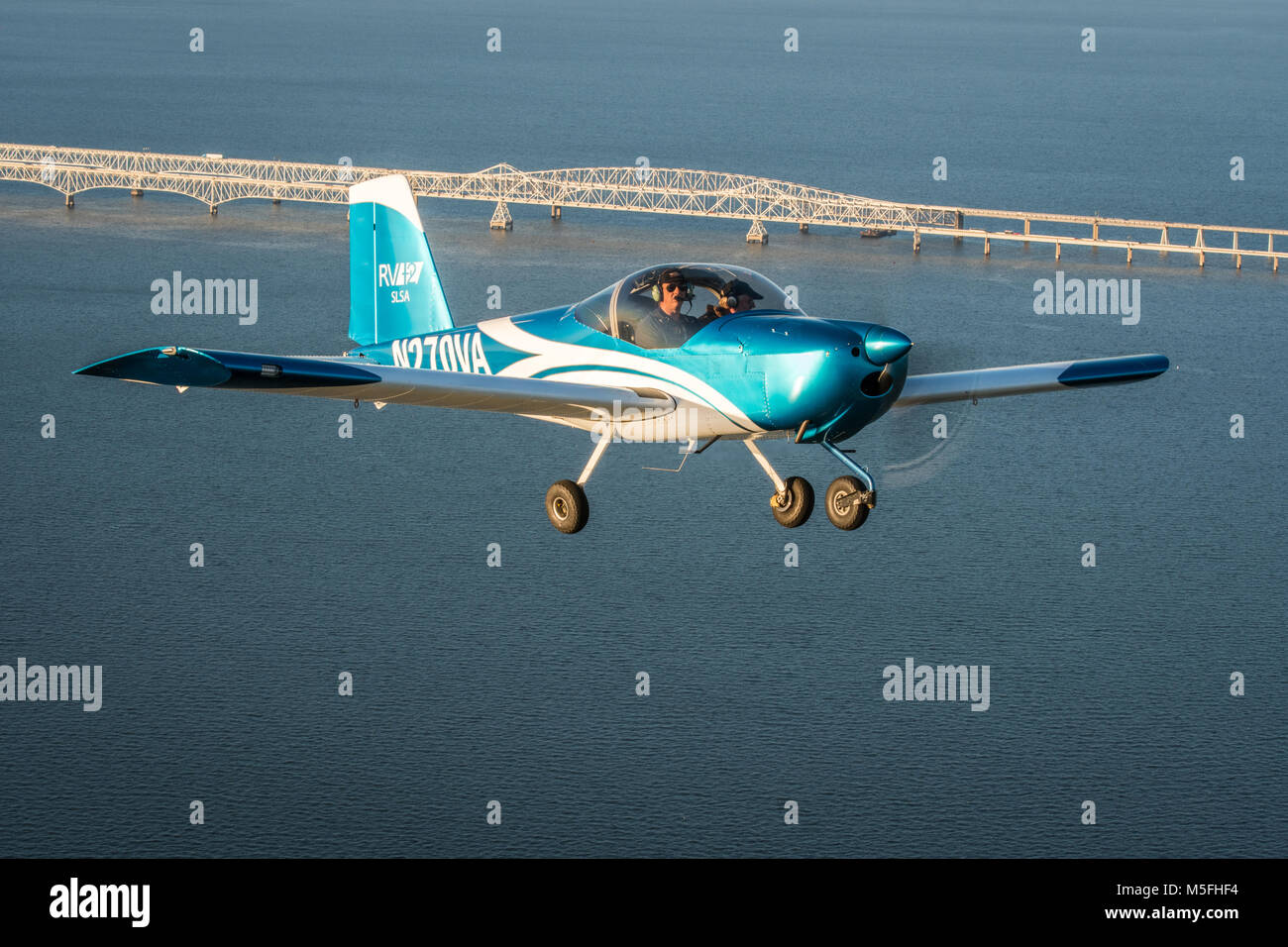 Male pilot operates blue Vans RV-12 light sport aircraft flying over ...