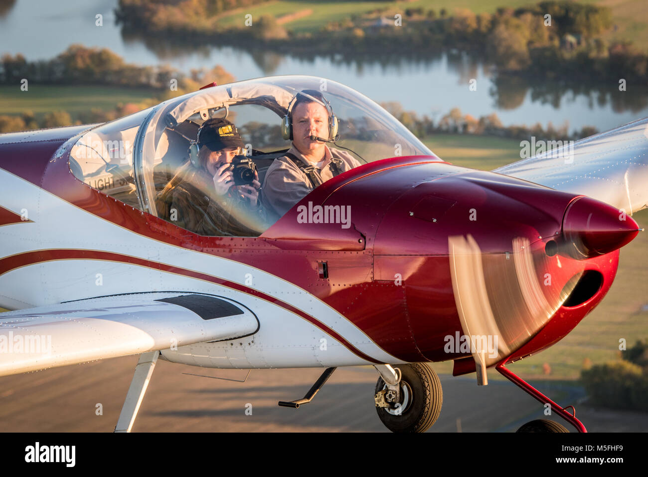 Close up of male pilot operating blue Vans RV-12 light sport aircraft with female photographer, Stevensville, Maryland. Stock Photo