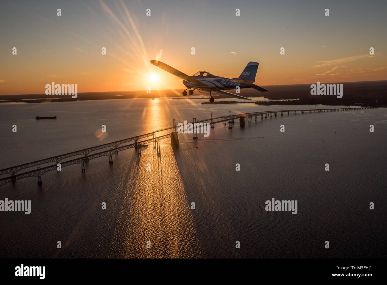 Blue Vans RV-12 light sport aircraft flying towards the setting sun ...