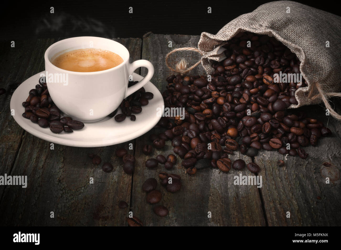Roasted coffee beans and coffee cup on wooden table Stock Photo - Alamy