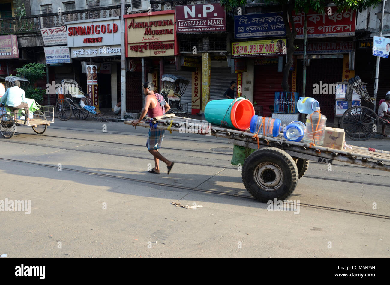 man carrying plastic buckets on hand pulled cart, Kolkata, West Bengal, India, Asia Stock Photo
