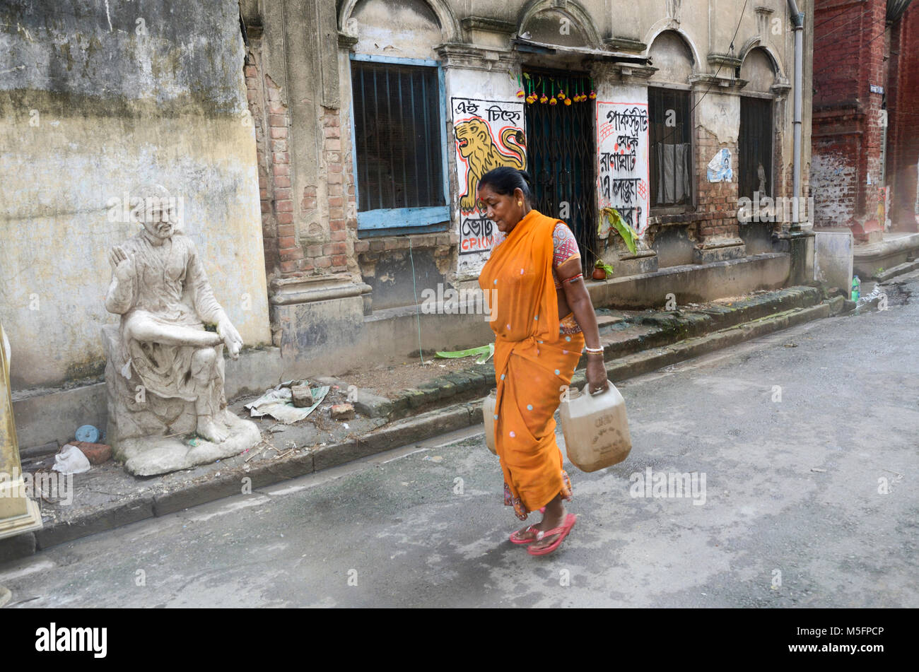 Sai Baba idol, woman carrying water in plastic cans, Kolkata, West Bengal, India, Asia Stock Photo