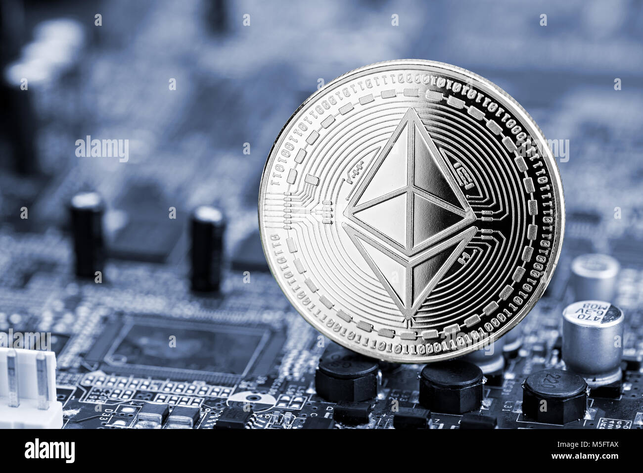 ethereum silver coin on blue motherboard chip digital mining computer hardwarecrypto currency financial background concept Stock Photo