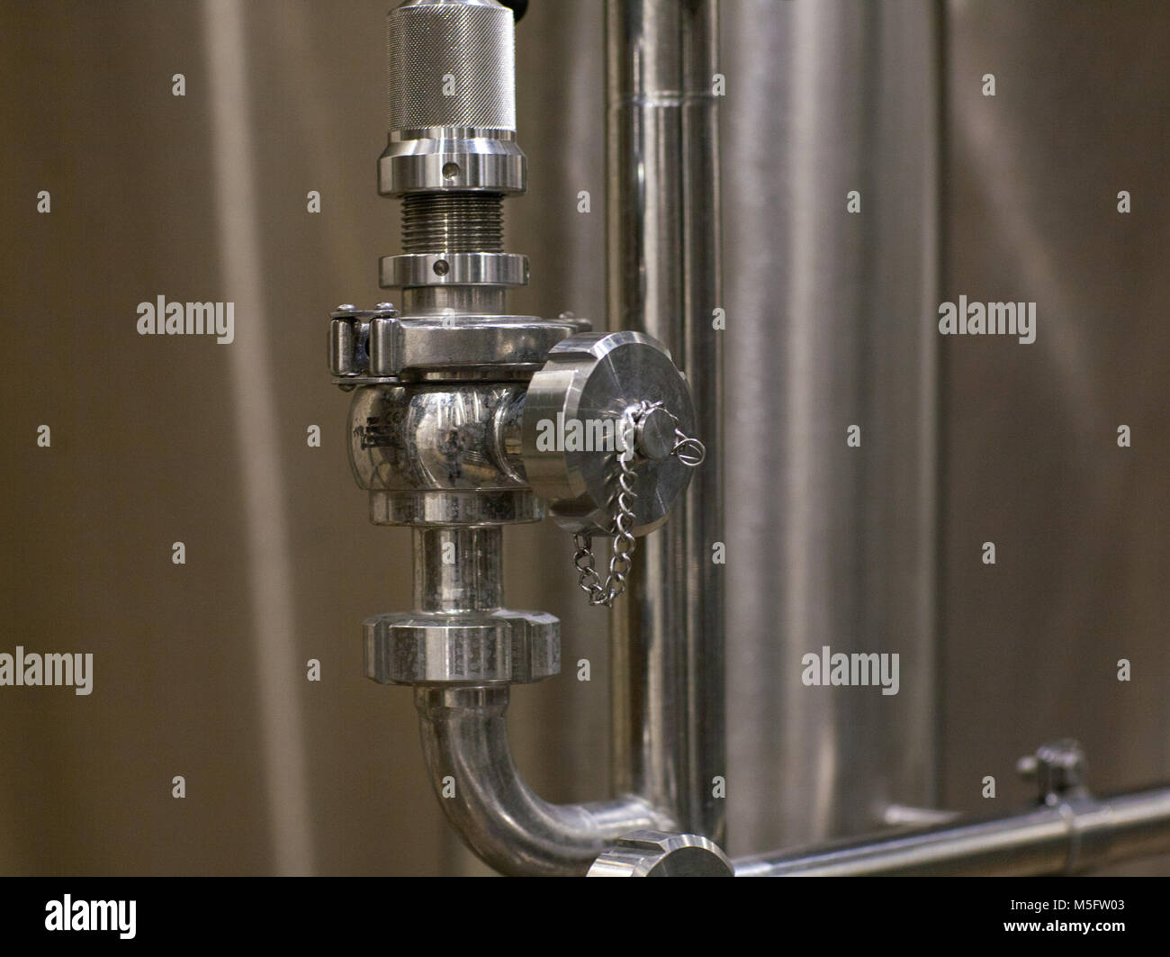 Valves and pipes made of white metal, located on the tanks, which brewed beer in the brewery