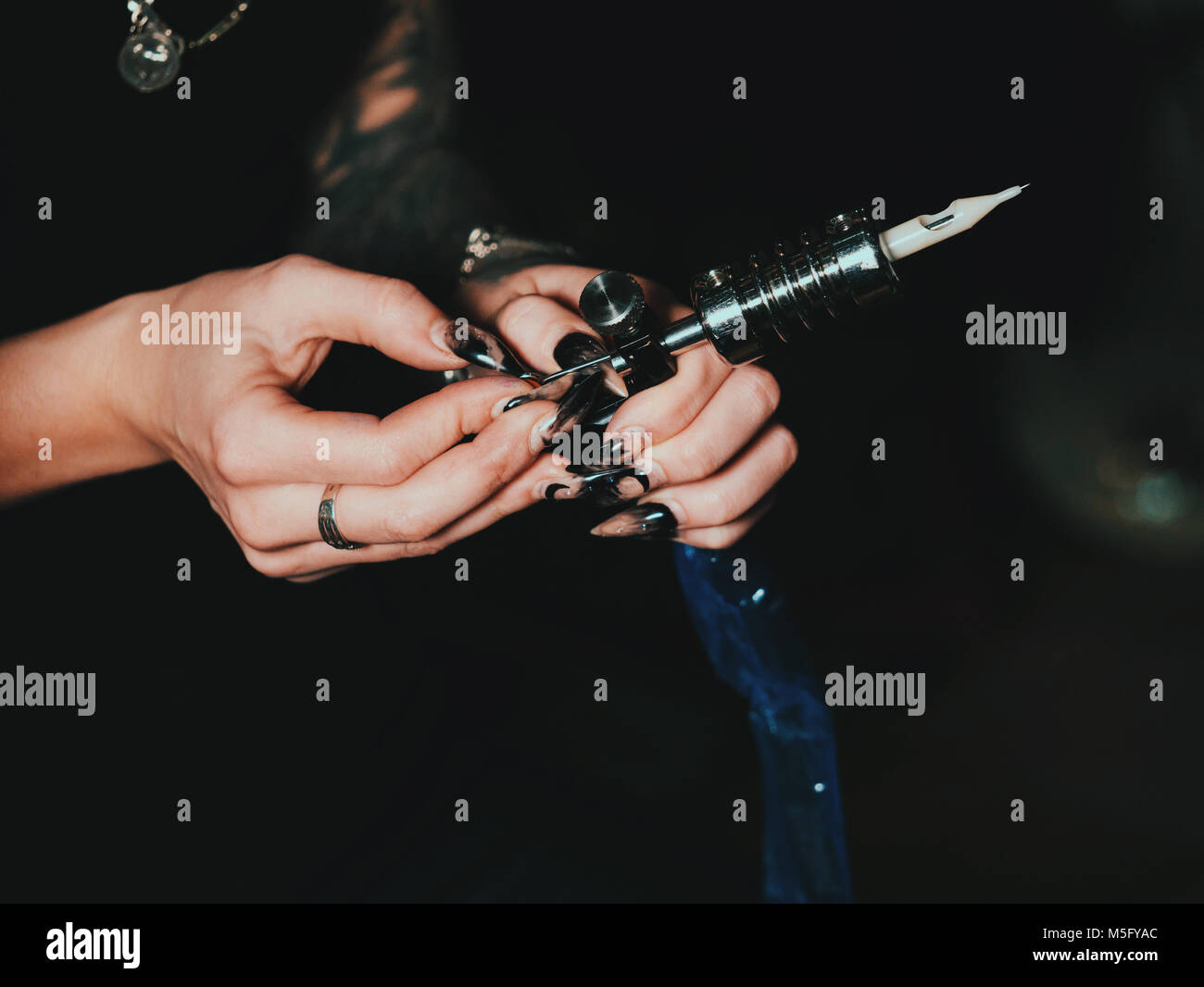 The female tattooist assembles a tattoo machine, puts a needle inside