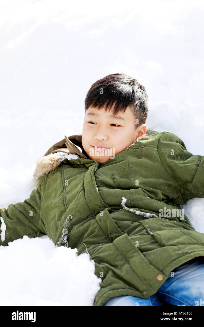 boy lay down on the snow and enjoy snow in the winter Stock Photo
