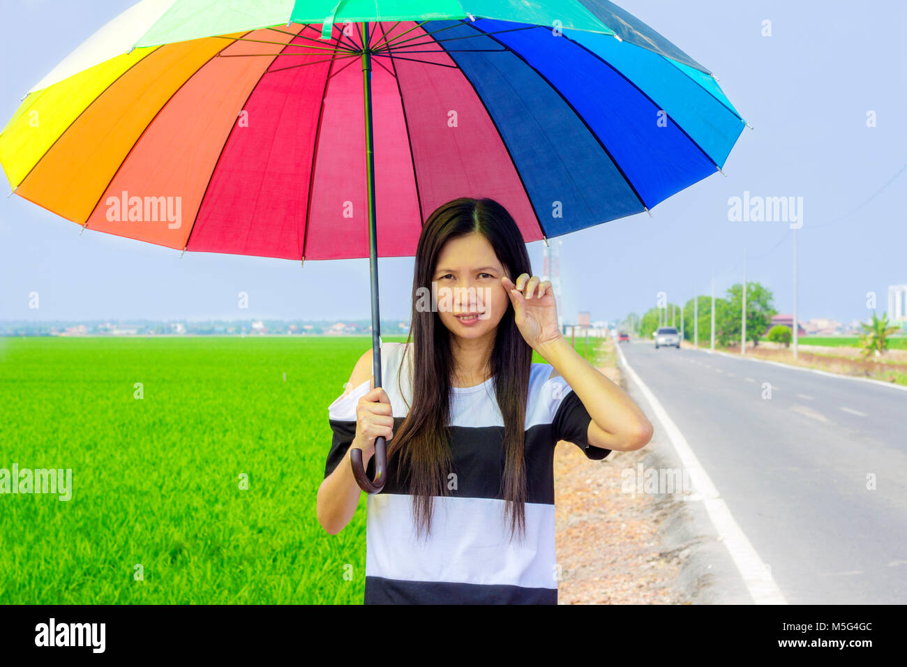 asian woman with umbrella standing beside the paddy field of Sekinchan in a hot sunny day and sweating Stock Photo