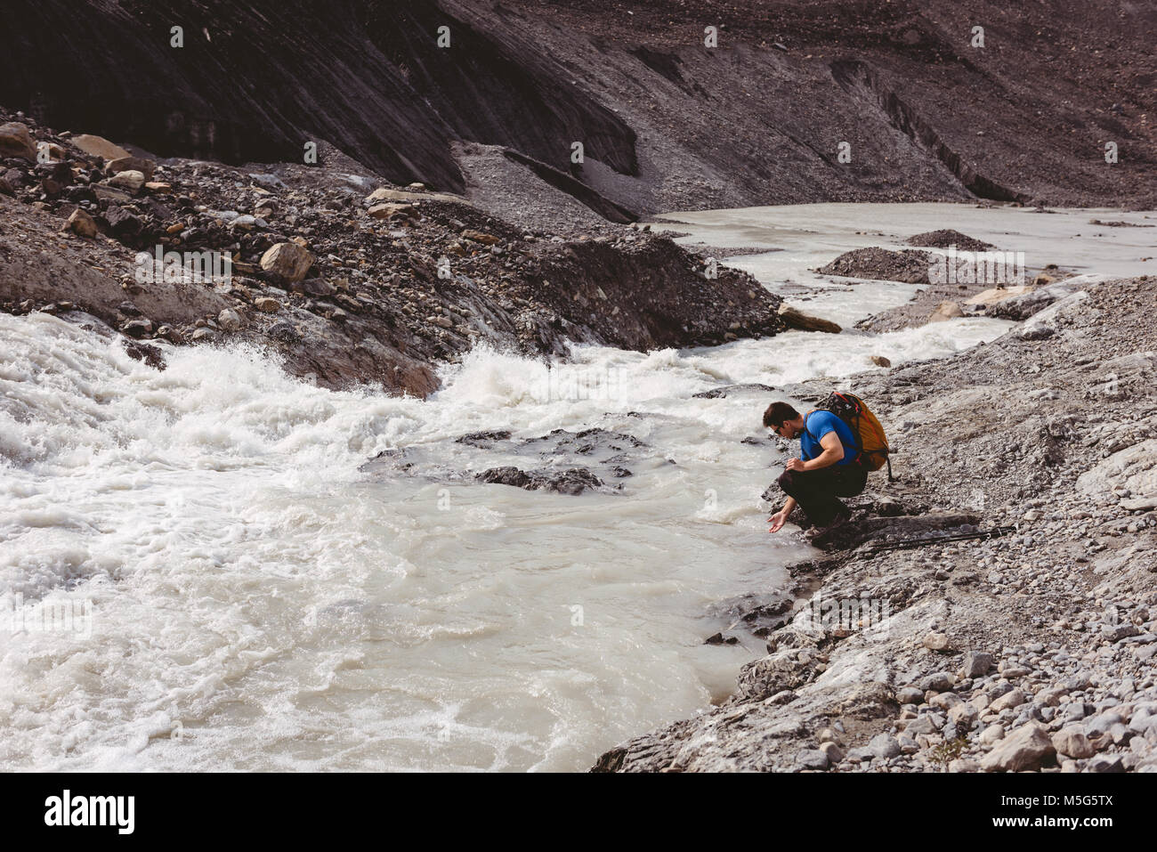 Male hiker washing his hands in river Stock Photo