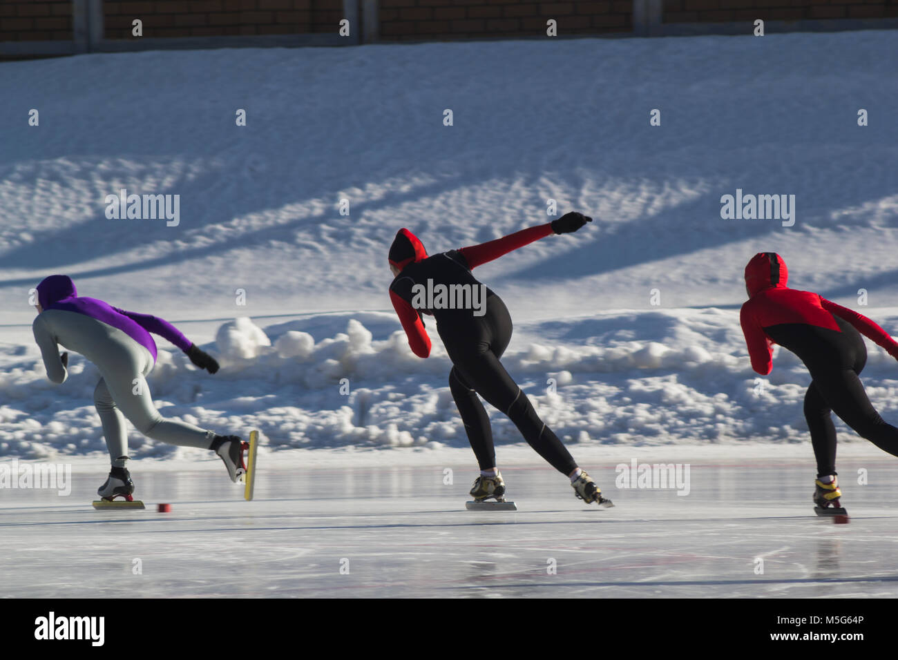 Speed skating competition on ice rink at winter sunny day children's