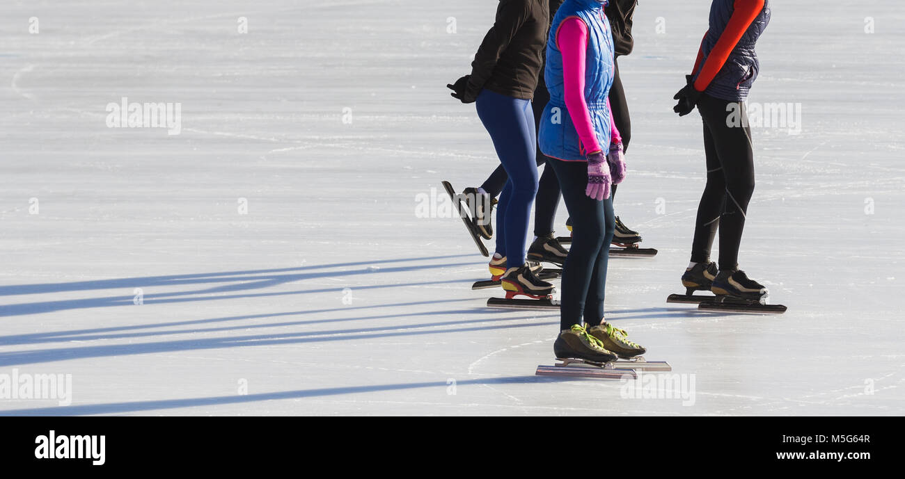 Speed skating sportsmen on competition ice rink at winter sunny day