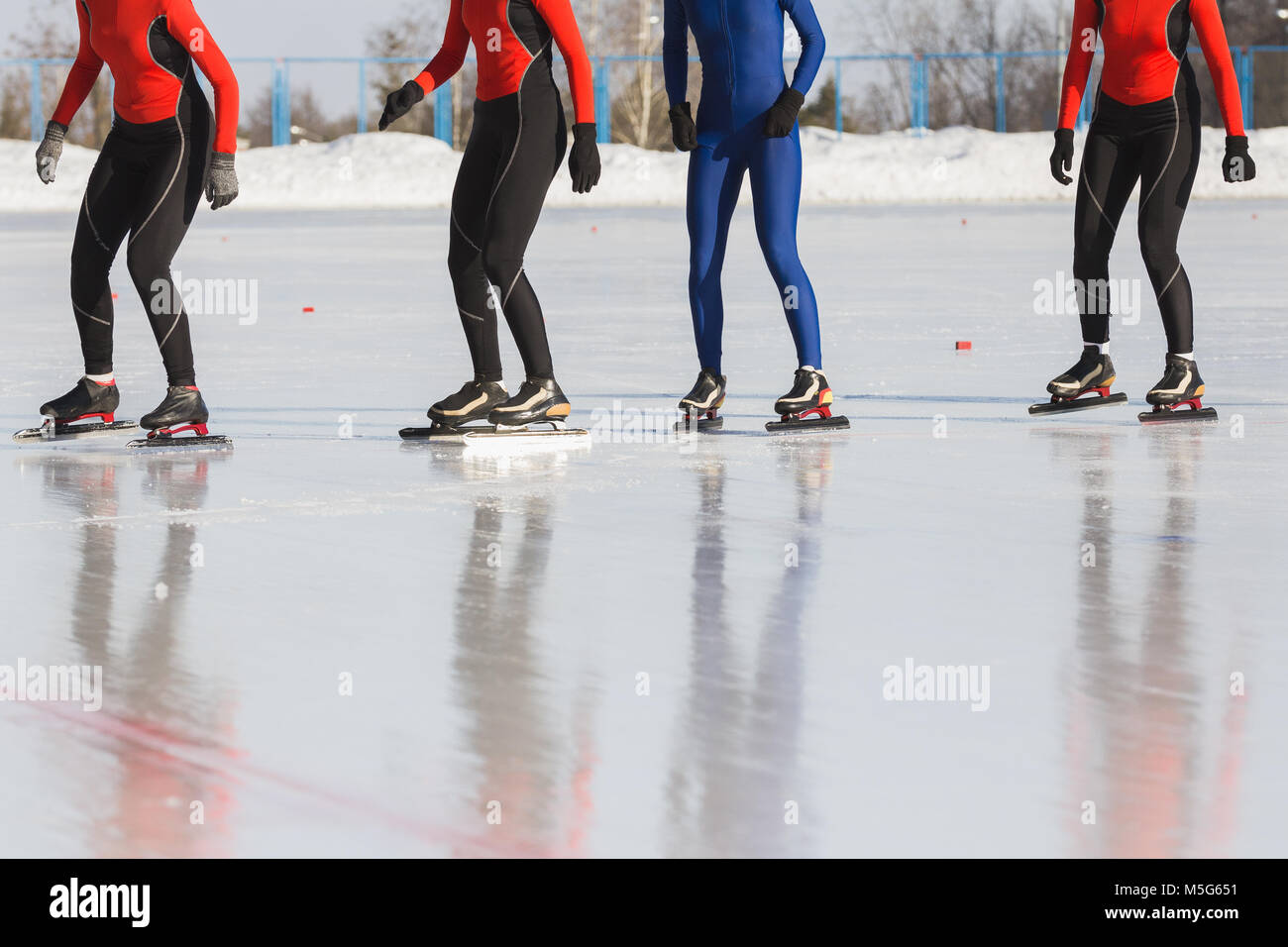 Speed skating competition on ice rink at winter sunny day sportsmen