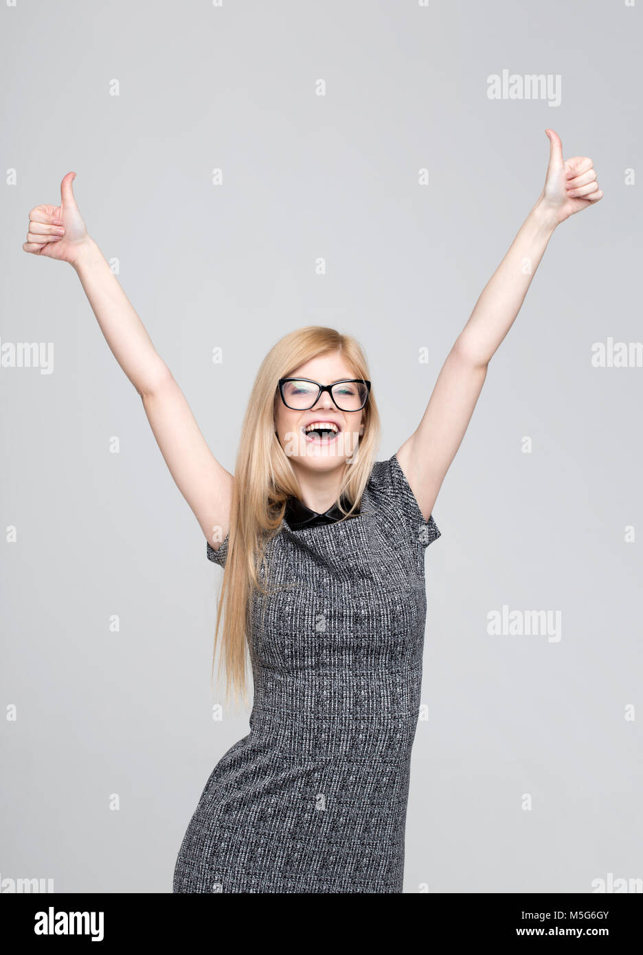 Happy young blonde caucasian woman winning hands and thumbs up, studio shoot Stock Photo