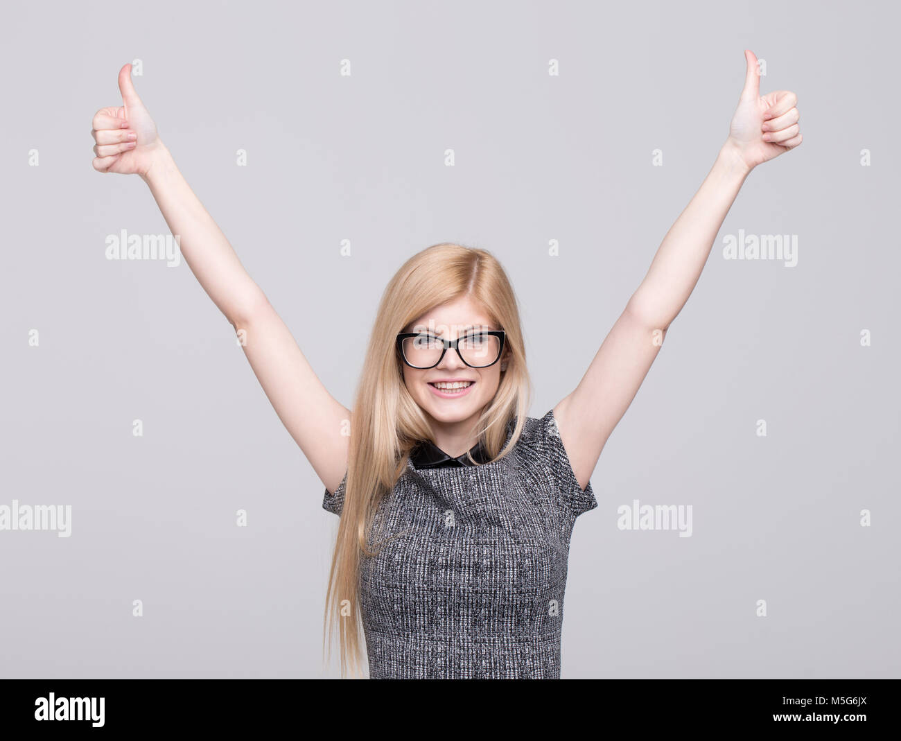 Young blonde caucasian woman in eyeglasses hands and thumbs up portrait, studio shoot Stock Photo