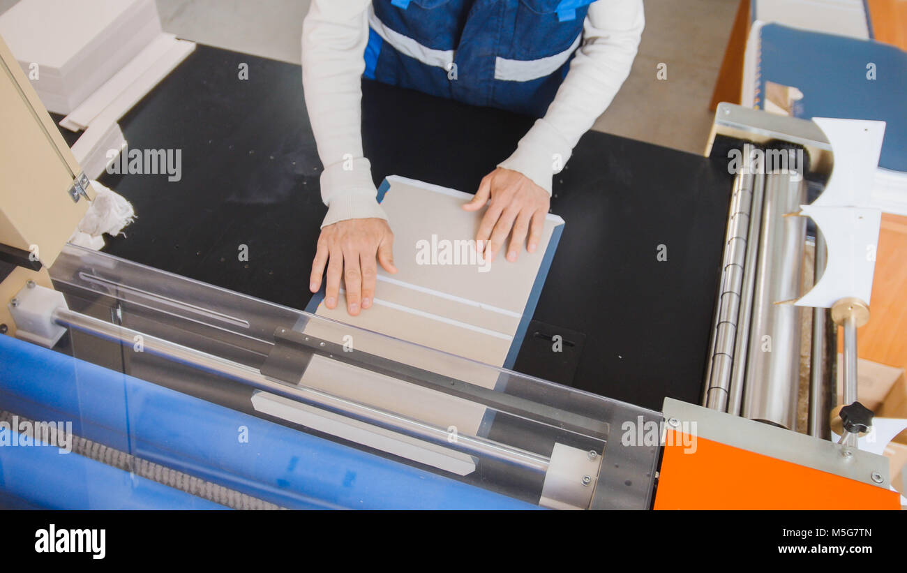 The operator of printing production pulls a printed sheet of paper