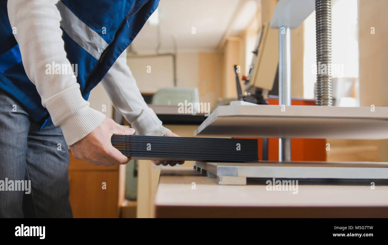 Printing process in printing press machine - worker inserts paper sheets, close up Stock Photo