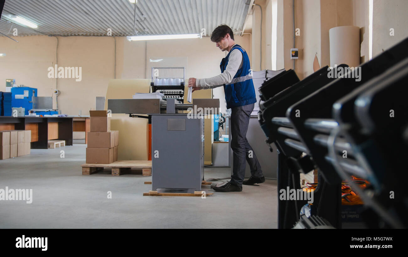 Worker and printing machine, polygraph industry Stock Photo