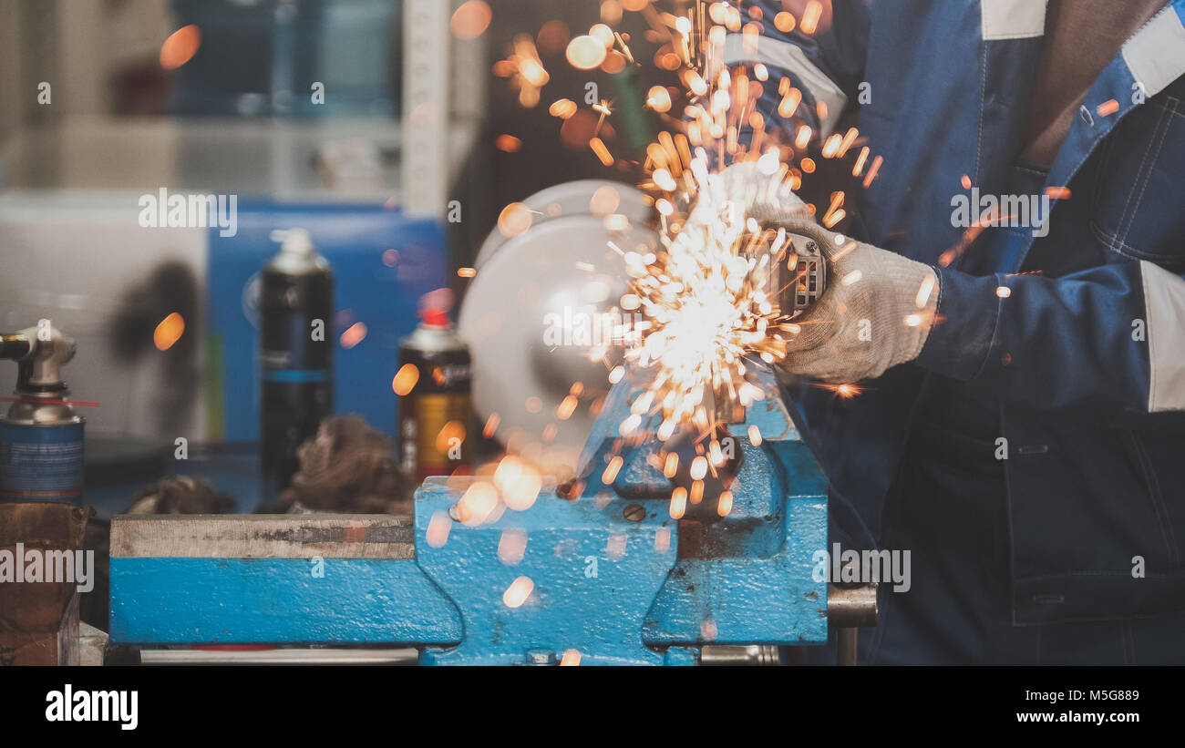 Car service worker grinding metal construction with a circular saw