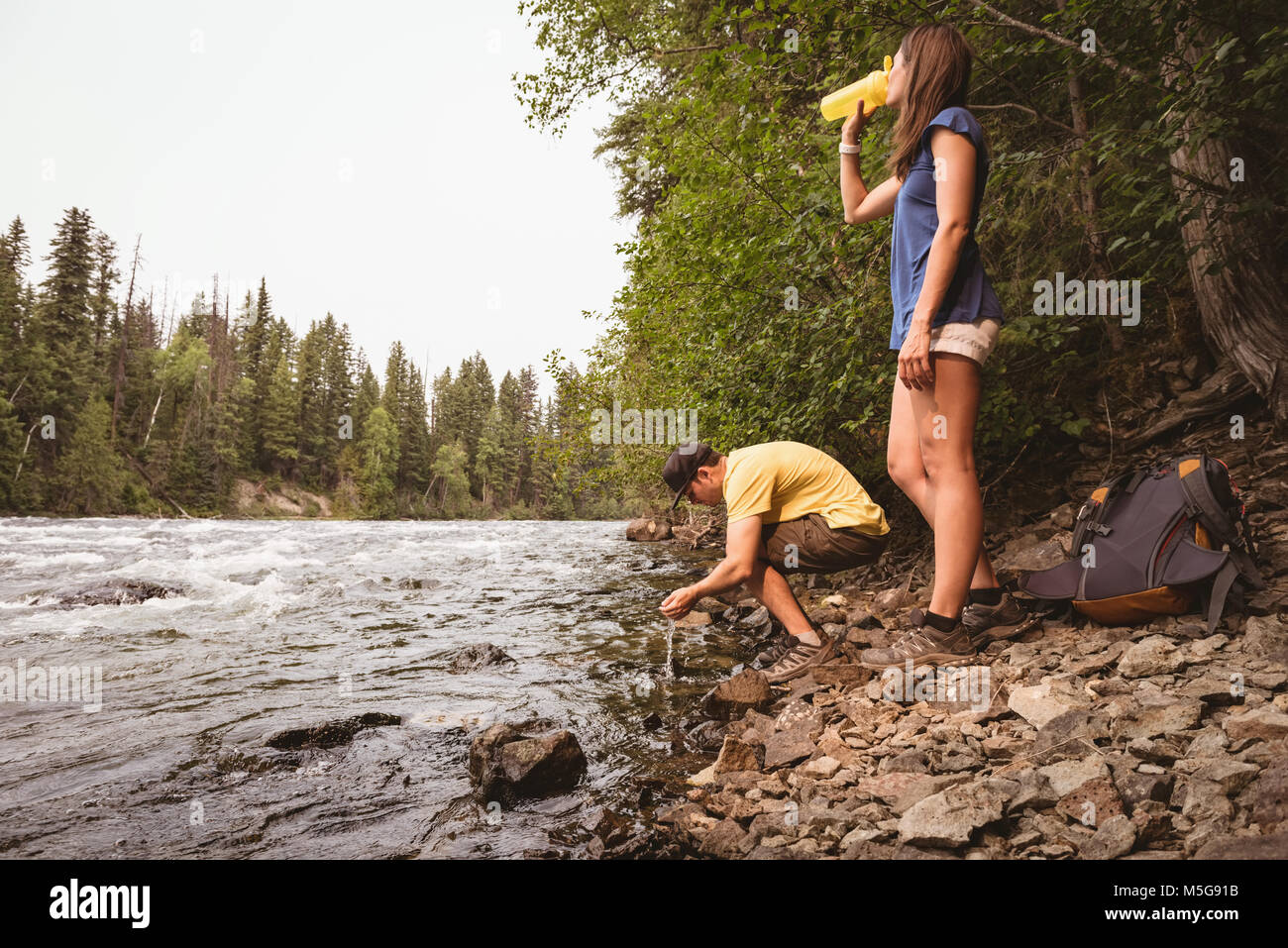 Couple drinking water near river Stock Photo Alamy