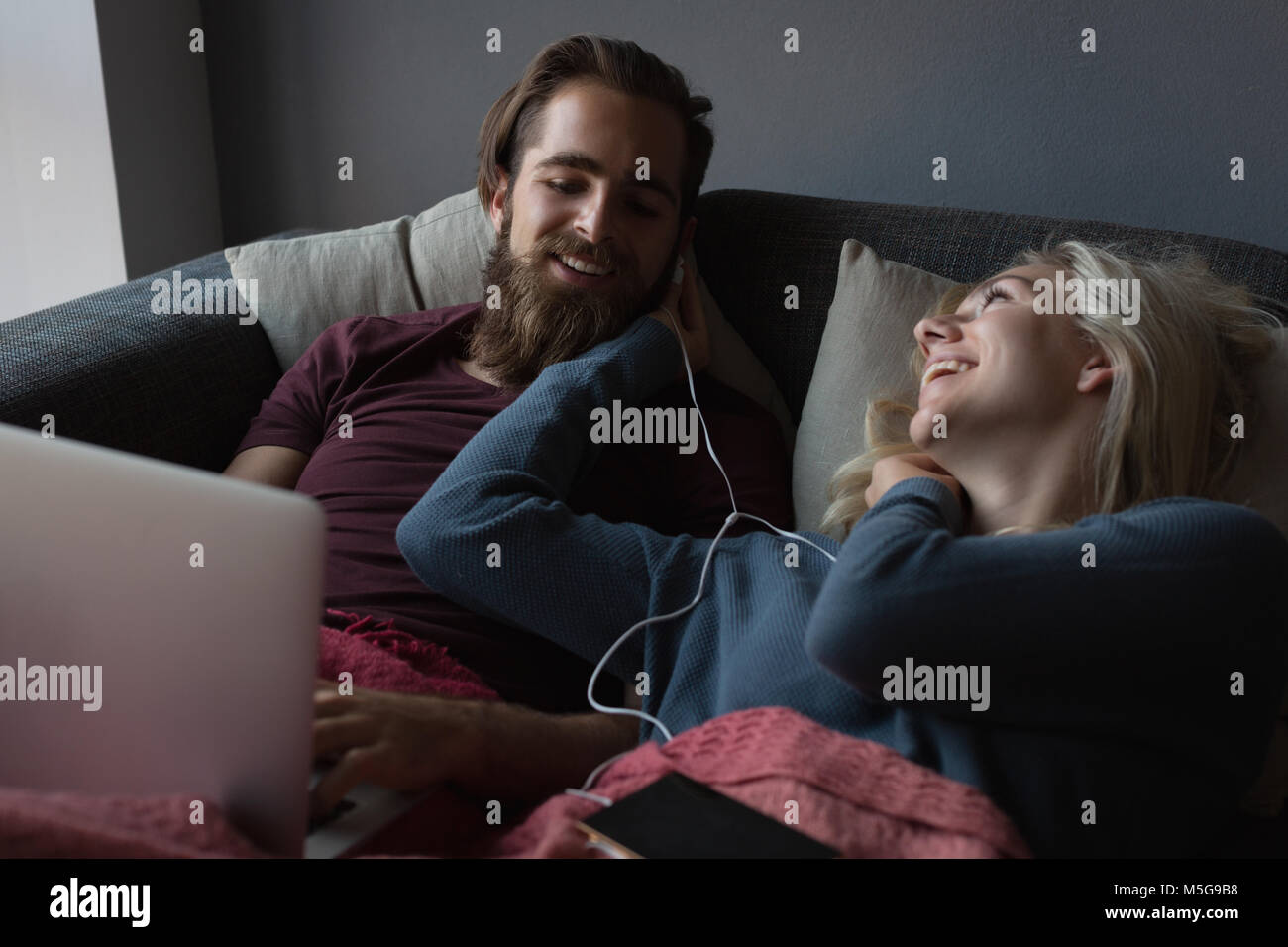 Couple using laptop in living room Stock Photo - Alamy