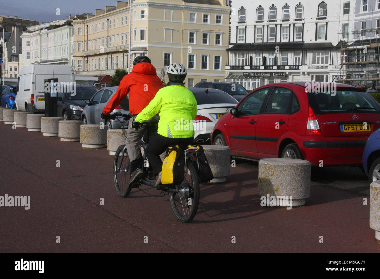 A REAR VIEW OF A COUPLE RIDING A TANDEM CYCLE ON A PAVEMENT CYCLE LANE