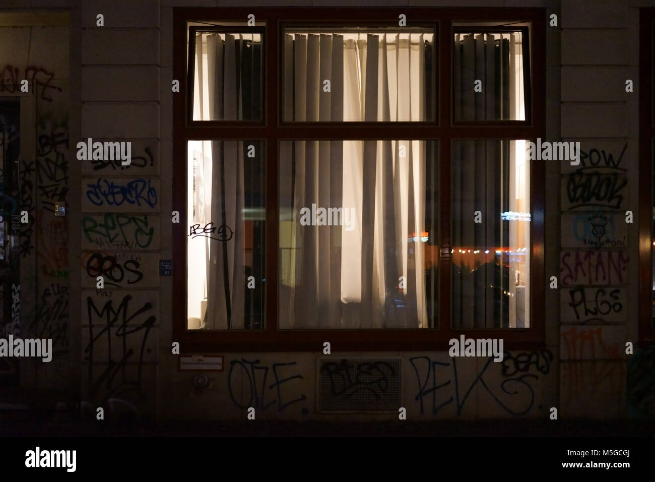 An Illuminated Room Window With Drawn Curtains At Night In A